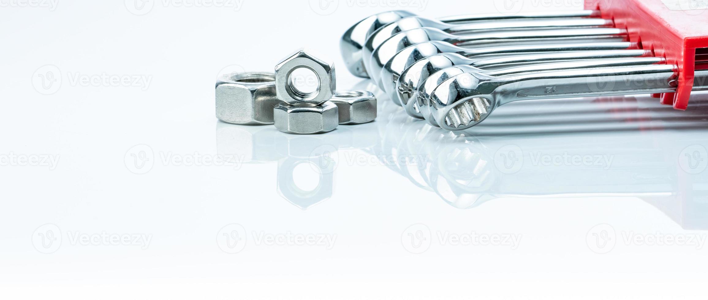 Metal hexagon nuts and chrome wrenches isolated on white background. Mechanic tools for maintenance. Hardware tool. Fastener with a threaded hole. Set chrome spanner wrench and nuts. Silver wrenches. photo