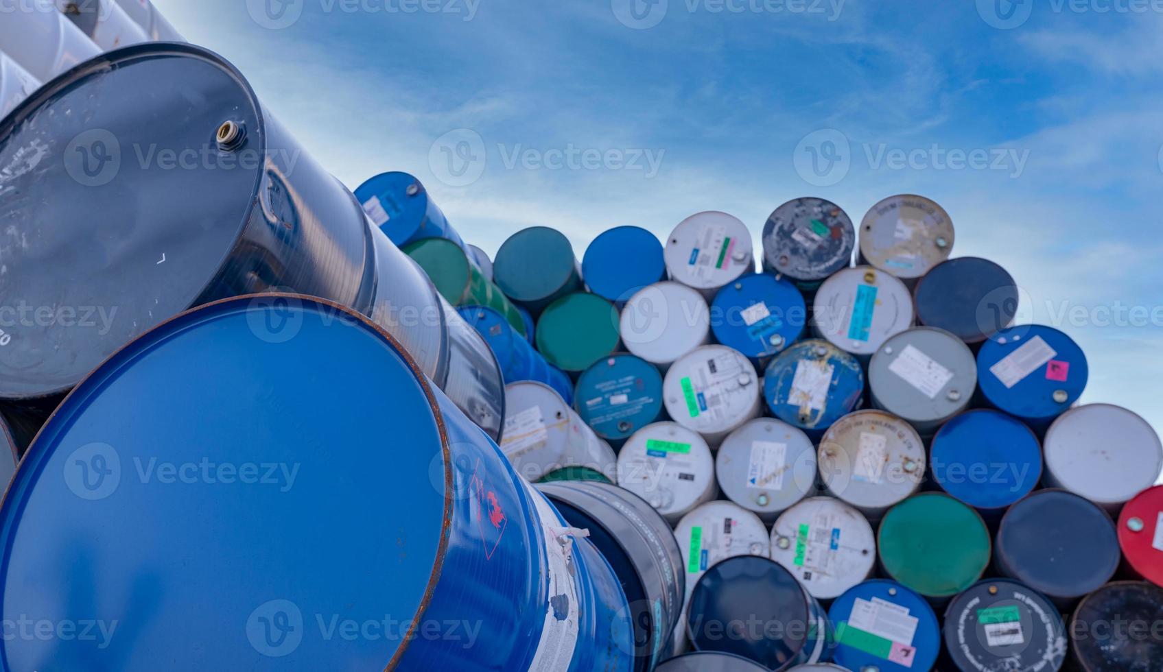 Old chemical barrels. Big stack of blue oil drum against sky. Steel oil tank. Toxic waste warehouse. Hazard chemical barrel with warning label. Industrial waste. Empty chemical barrels in factory. photo