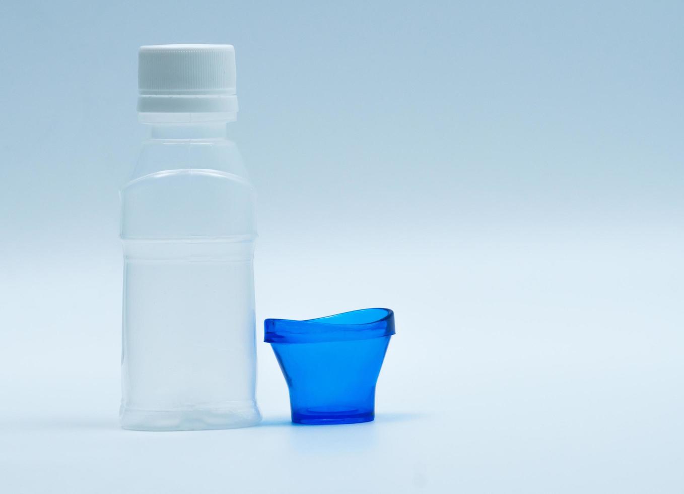 loción ocular estéril en botella de plástico blanco con baño de ojos azul y espacio de copia y etiqueta en blanco. lavado de ojos después de la contaminación del contacto con el medio ambiente o después de nadar en una piscina contaminada con cloro. foto