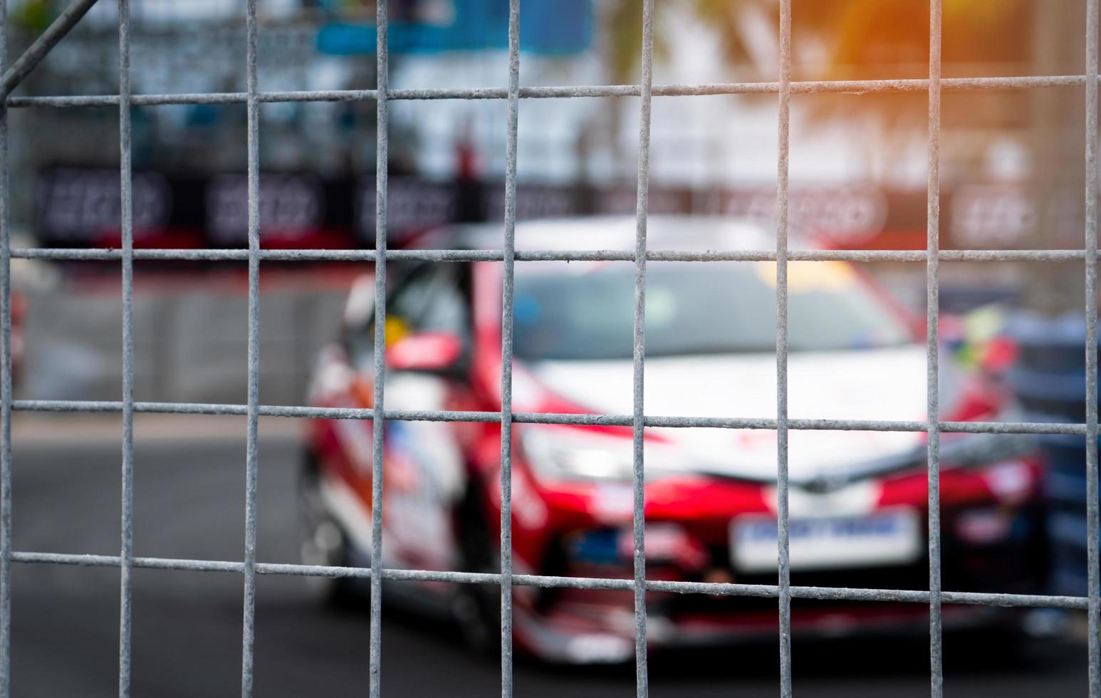 Motorsport car racing on asphalt road. View from the fence mesh netting on blurred car on racetrack background. Super racing car on street circuit. Automotive industry concept. photo