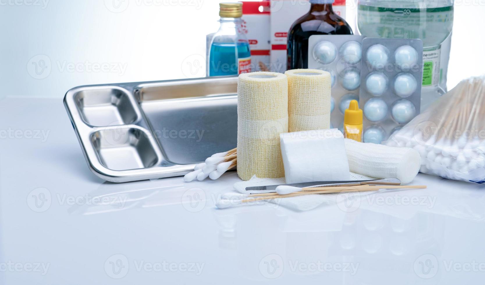 Wound care dressing set and stainless steel plate, forceps, cotton stick, conform bandage, elastic cohesive retention bandage, alcohol, normal saline bottle, and povidone-iodine. Medical supply. photo