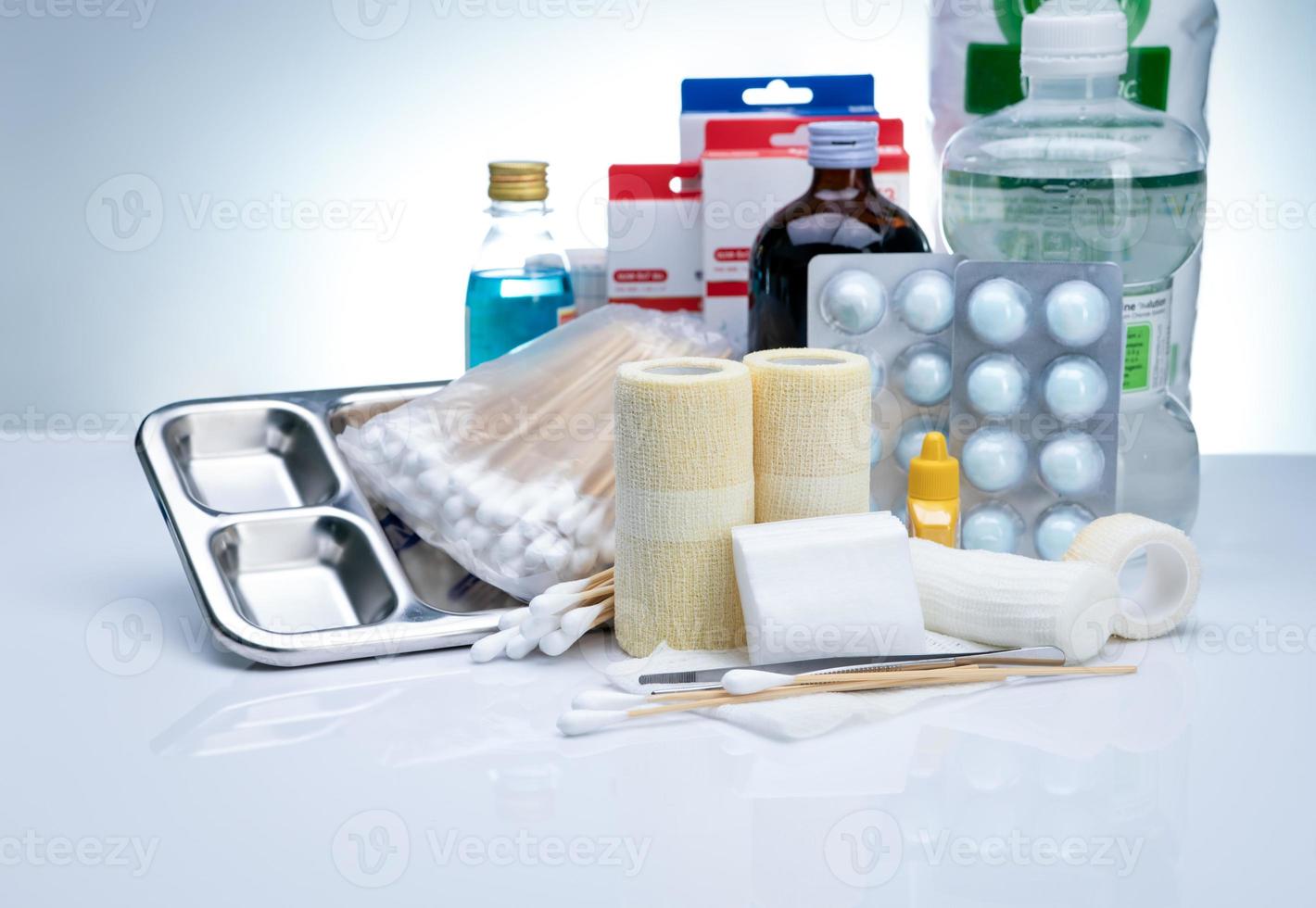 Wound care dressing set and stainless steel plate, forceps, cotton stick, conform bandage, elastic cohesive retention bandage, alcohol, normal saline bottle, and povidone-iodine. Medical supply. photo