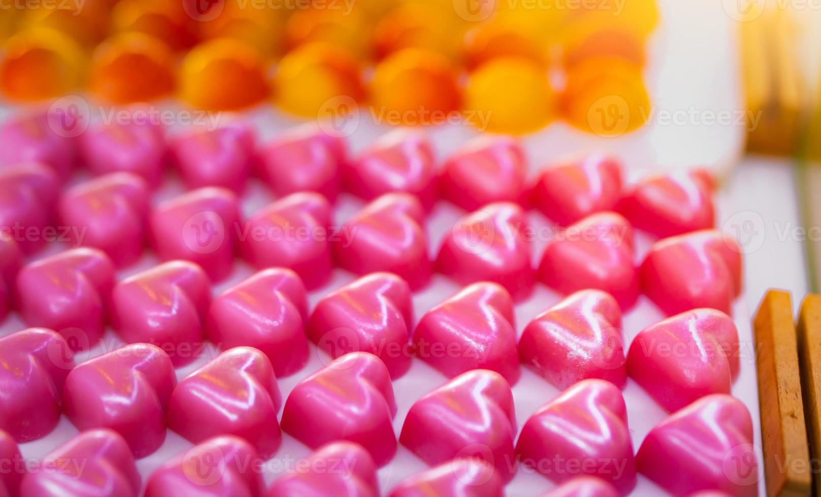 Pink heart shape chocolate. Valentine's day gift. White chocolate ganache with rose scent on white plate. Chocolate pralines. Luxury chocolate candy. Delicious dessert. Food for love and dating. photo