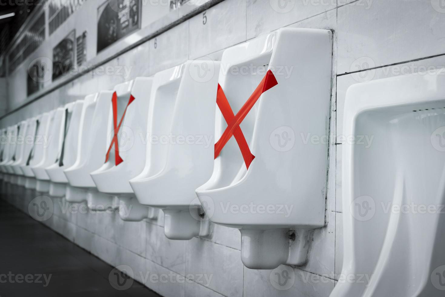 White ceramic urinals in men public toilet. Social distancing in men restroom to prevent coronavirus pandemic. Man bladder health with urinary incontinence problem. Urine infections. Male latrine WC. photo