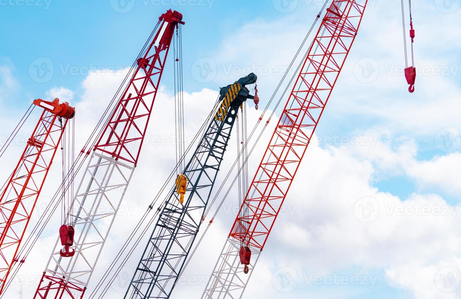 Crawler crane against blue sky and white clouds. Real estate industry. Red crawler crane use reel lift up equipment in construction site. Crane for rent. Crane dealership for construction business. photo