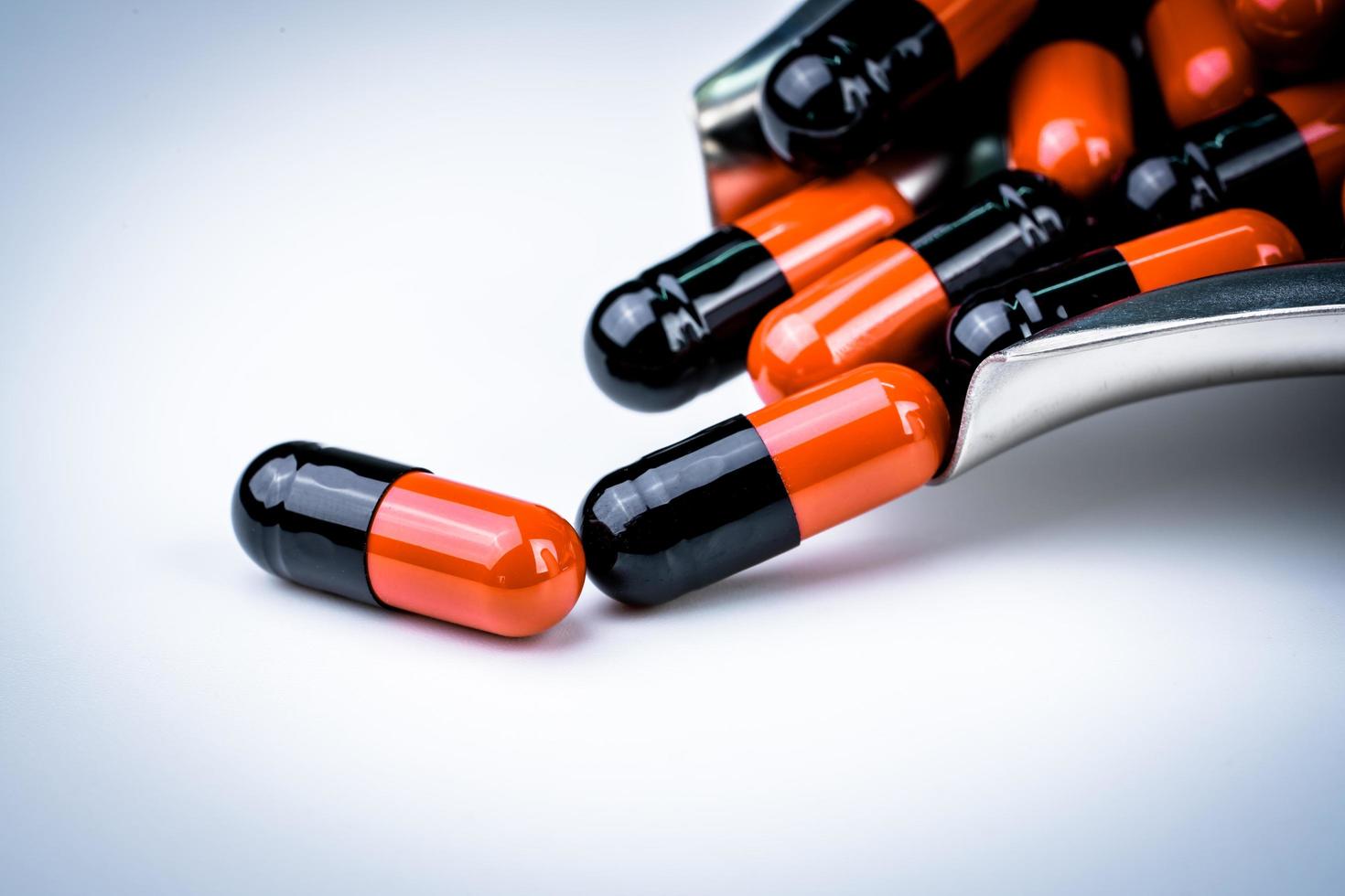 Selective focus of orange and black capsule pills on stainless steel drug tray. Antibiotics resistance. Global healthcare. Antibiotics drug resistance. Antimicrobial capsule pills. Pharmacy background photo