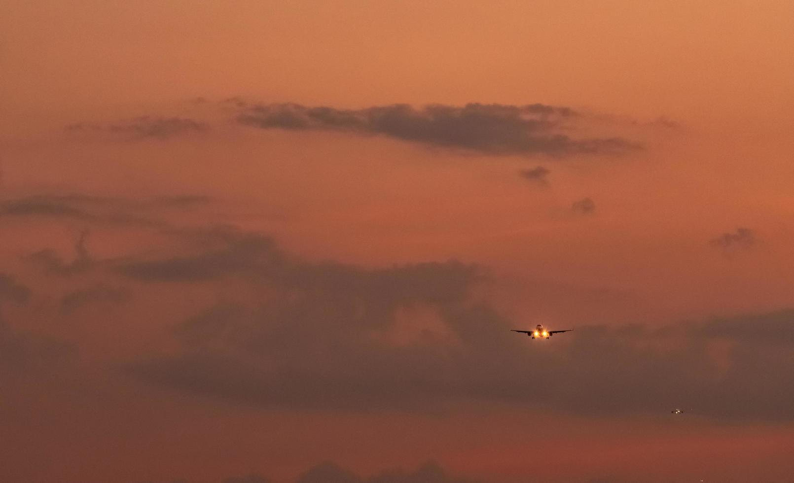 Commercial airline. Passenger plane landing at airport with beautiful sunset  sky and clouds. Arrival flight. Airplane flying in a line for landing. Aircraft open light in the evening flight. photo