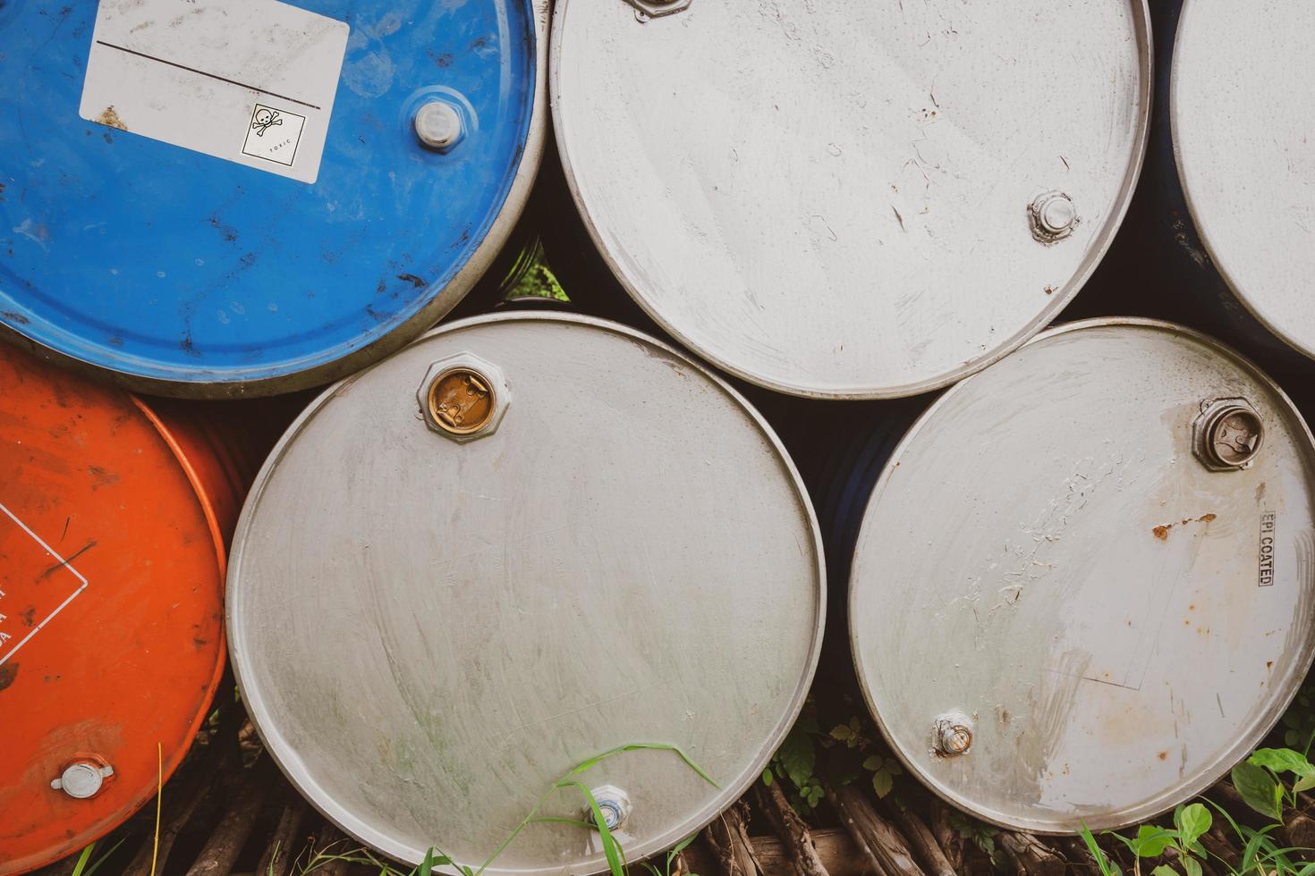 viejos barriles químicos. tambor de aceite azul y naranja. tanque de aceite de acero. almacén de residuos tóxicos. Barril químico de peligro con etiqueta de advertencia. residuos industriales en tambor de metal. almacenamiento de residuos peligrosos en la fábrica. foto