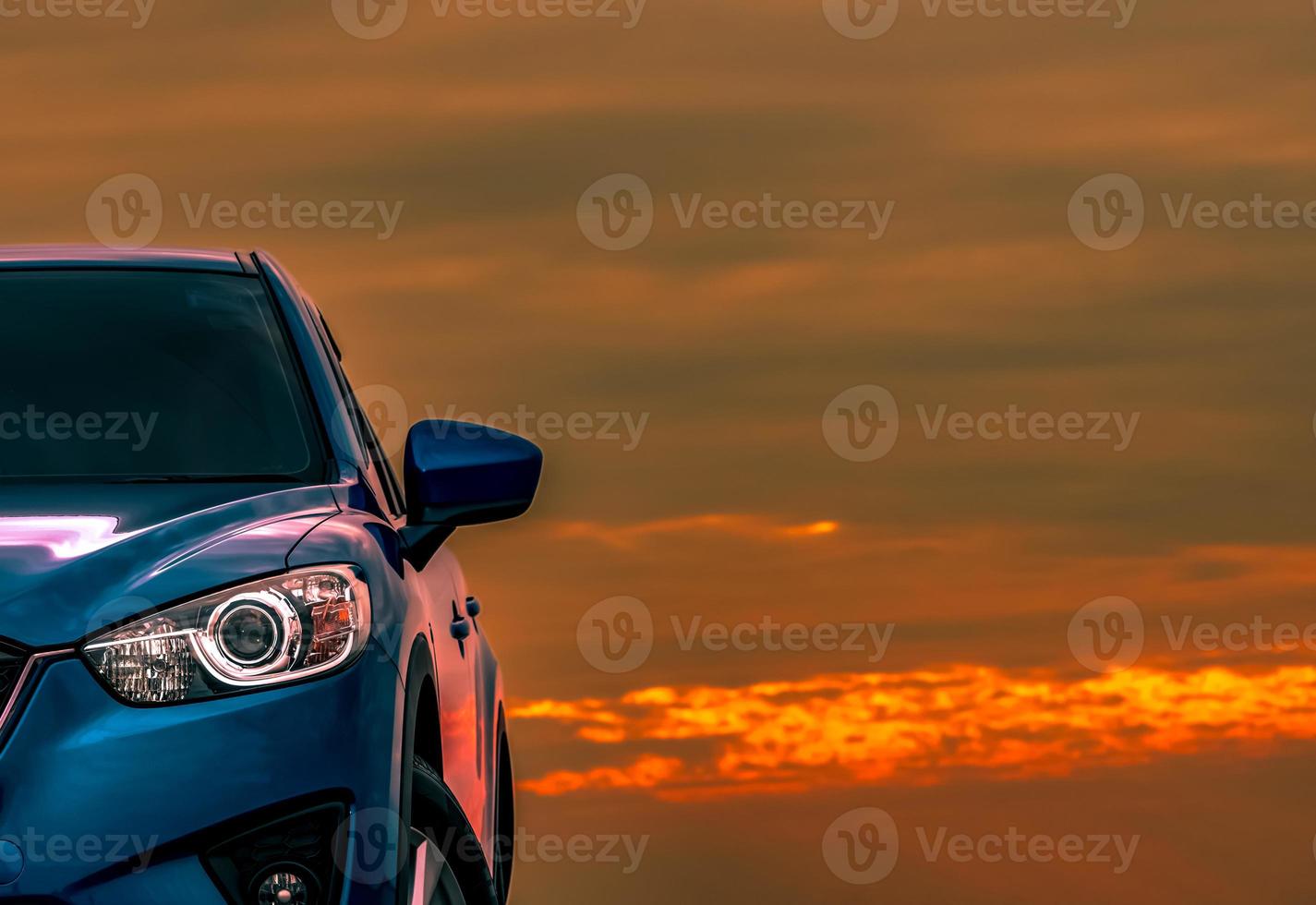 Front view of blue compact SUV car with sport and modern design parked on concrete road at sunset with beautiful orange sky. Electric car technology. Automotive industry. Car care business background. photo