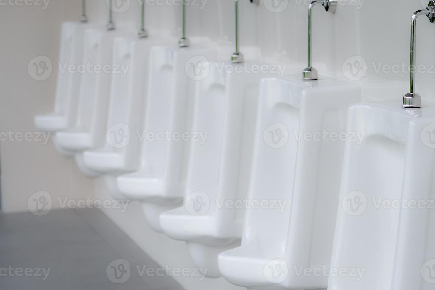 White urinals in men public toilet. Ceramic urinals in a row in men restroom. Man bladder health with urinary incontinence problem concept. Urine infections. Male latrine WC. Comfort male toilet. photo