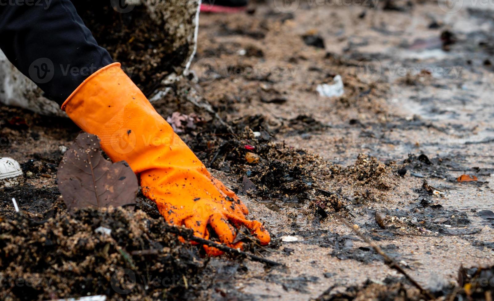 voluntarios recogiendo basura. contaminación del medio ambiente de la playa. voluntarios limpiando la playa con un fondo borroso. ordenar la basura en la playa. manchas de aceite en la playa. fuga de aceite al mar. foto