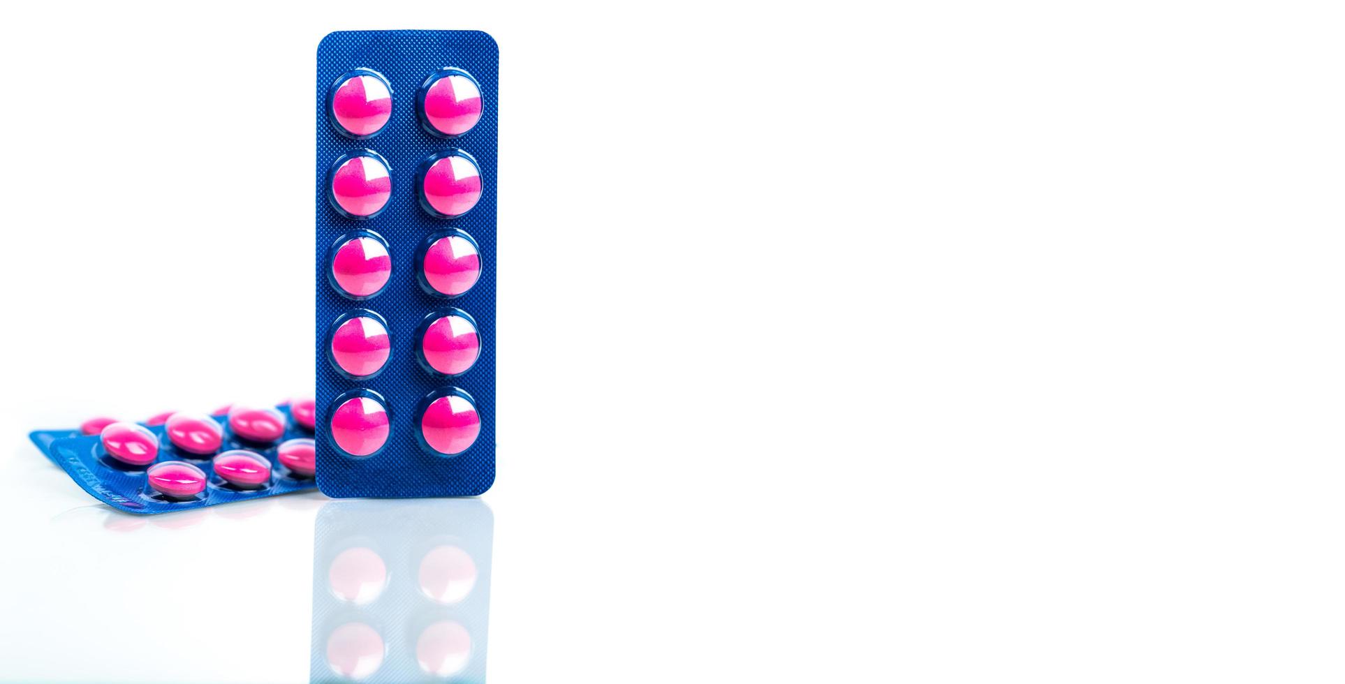 Pink tablets pill in blue blister pack isolated on white background. Painkiller medicine. Pharmaceutical industry. Medicine for treat migraine headache, fever, toothache. Pharmacy drugstore products. photo