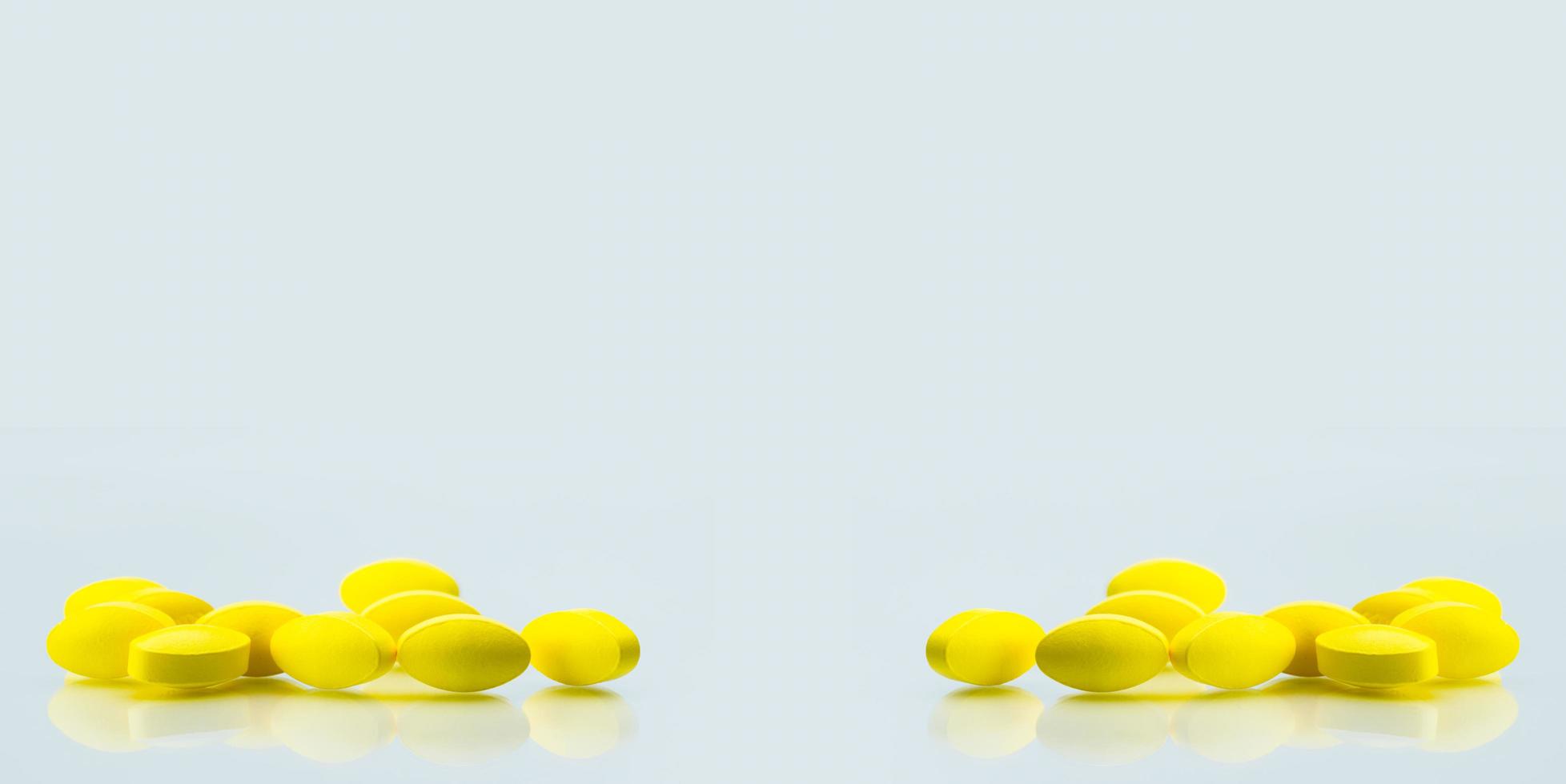 Yellow oval tablet pills with shadows on white background with copy space for text. Mild to moderate pain management. Pain killer medicine. photo