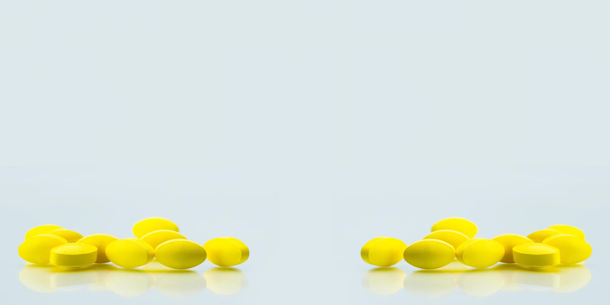 Yellow oval tablet pills with shadows on white background with copy space for text. Mild to moderate pain management. Pain killer medicine. photo