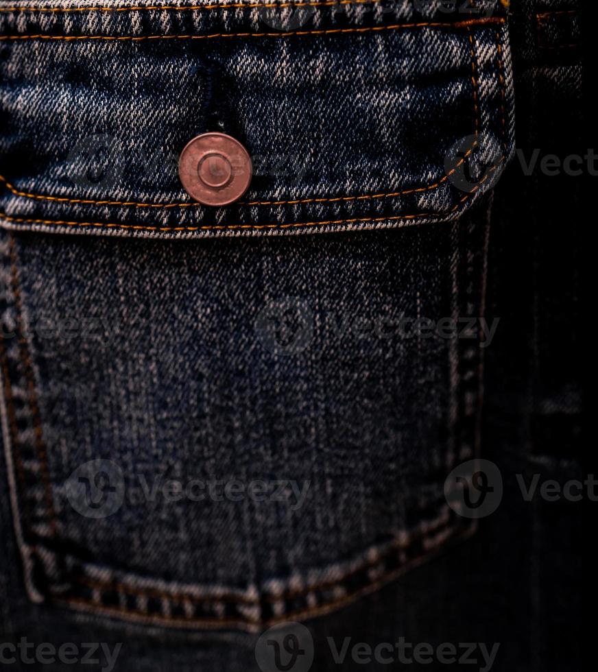 Selective focus on denim jean jacket pocket in clothes shop. Denim jacket pocket and button texture. Textile industry. Jeans fashion and shopping concept. Clothing concept. Denim jacket for sale. photo