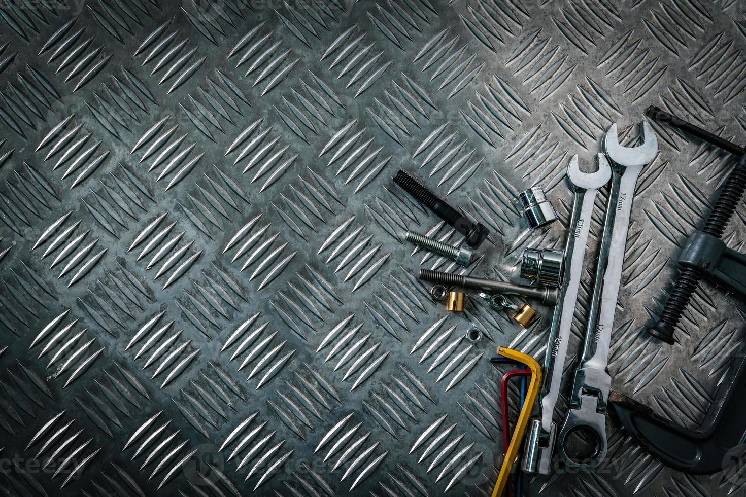 Top view of tools on industrial metal checker plate. Metal checkerplate for anti skid. Nut, bolts, and hex key on metal sheet floor. Silver bump ground with art pattern. Silver texture background. photo
