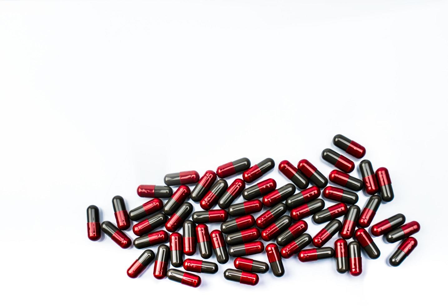 Pile of red-gray capsule pills on white background. Pharmaceutical industry. Pharmacy drugstore product. Pharmaceutical manufacturing. Pharmaceutics. Global healthcare concept. Many of capsule pills. photo