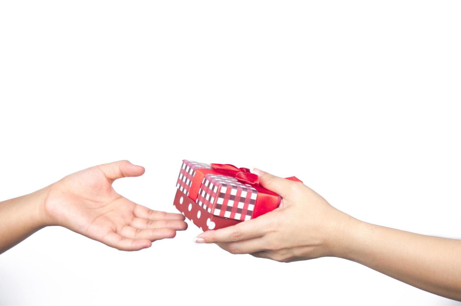 Closeup hands giving and receiving Christmas gift box wrapped with red ribbon isolated on white background photo