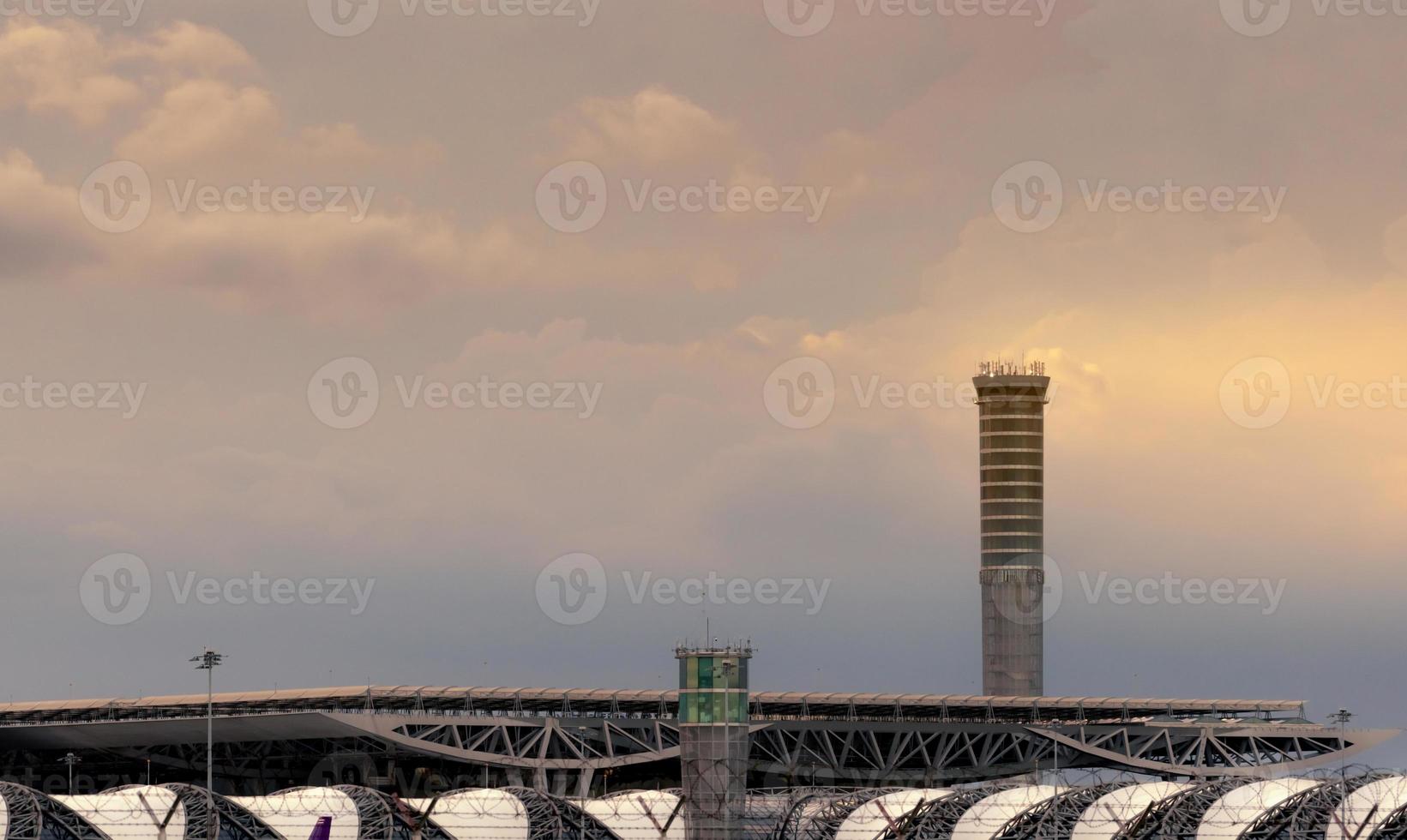 Airport roof and air traffic control tower in the airport. Airport traffic control tower for control airspace by radar. Aviation technology. Airport building with sunset sky and white clouds. photo