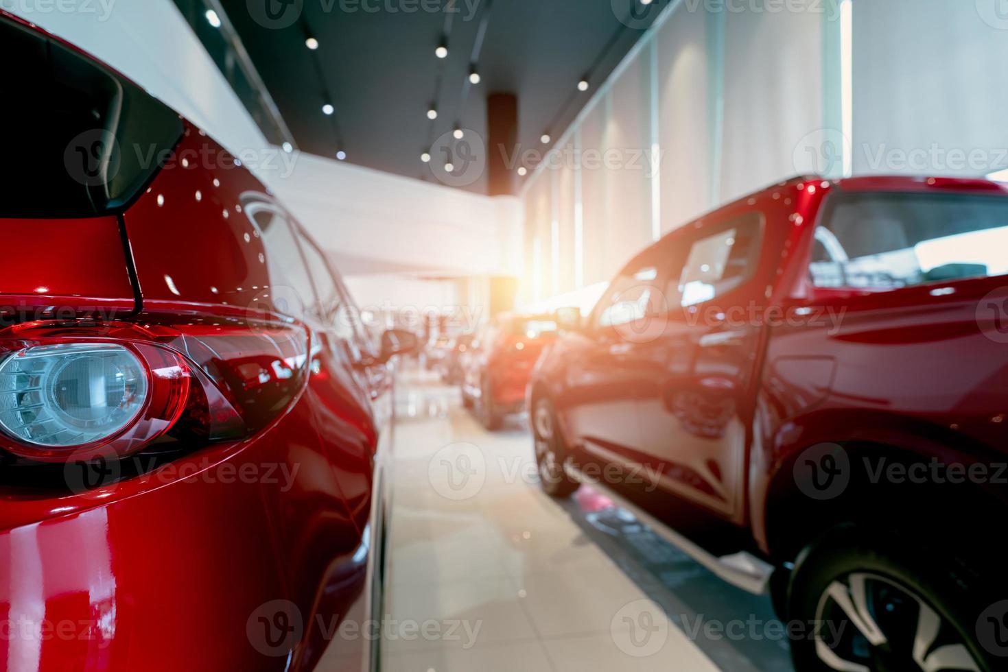 Rear view of red car parked in luxury showroom. Car dealership office. New car parked in modern showroom. Car for sale and rent business concept. Automobile leasing and insurance. Closeup tail light. photo