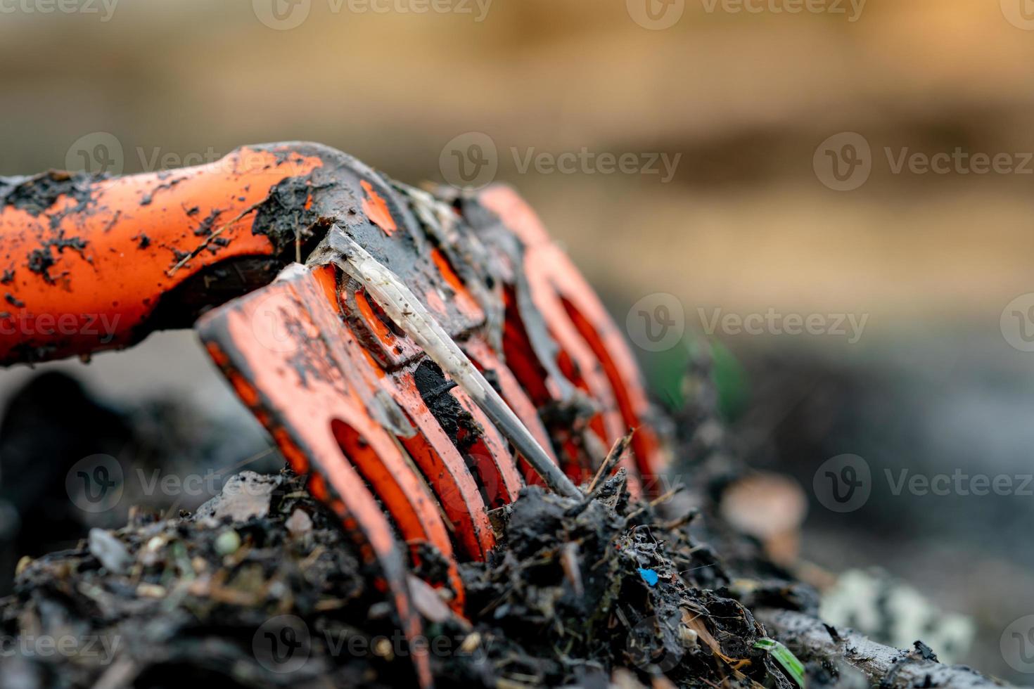 rastrillo naranja de primer plano sobre un montón de residuos plásticos sucios sobre un fondo borroso. el concepto de contaminación ambiental de la playa limpia la basura en la playa. basura del océano. costa contaminada. foto