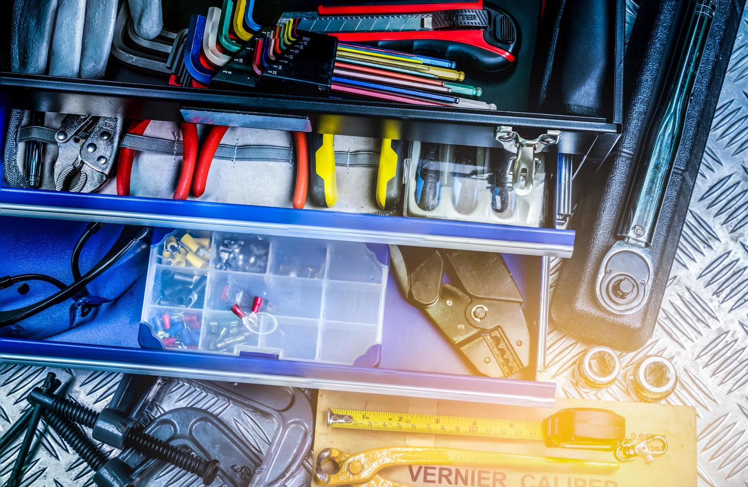 Top view of tools in box on checkered plate background in workshop. Service tools set. Home building and electrical tools. Plumber hand tools. Technician equipment for repair work. photo