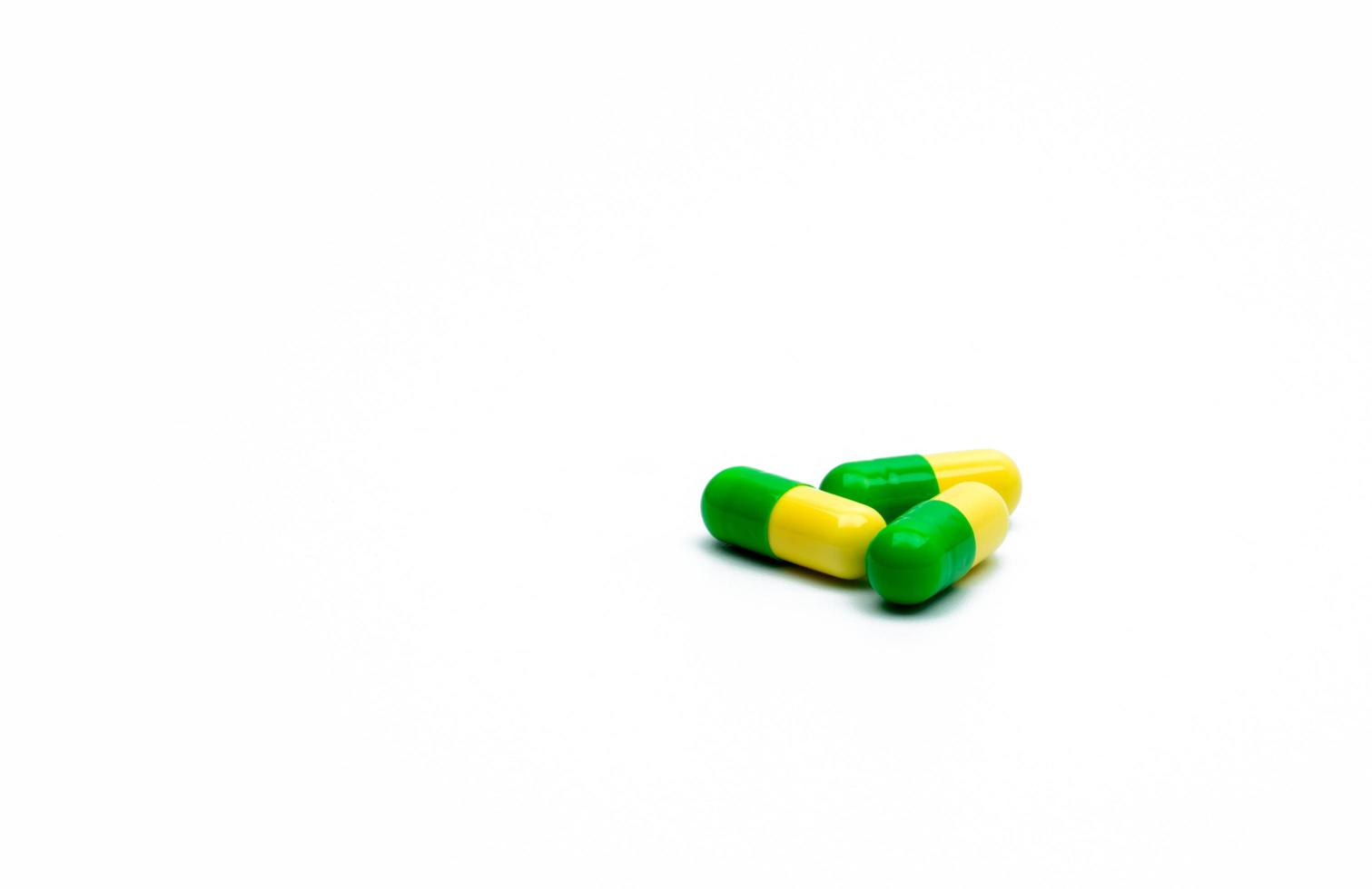 Green, yellow tramadol capsule pills on white background with shadows and copy space. Cancer pain management. Opioid analgesics. Drug abuse in teenage in Thailand. photo