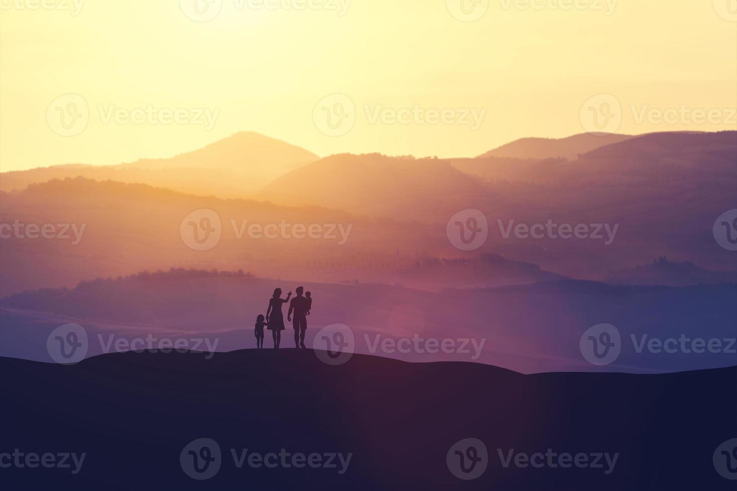 Family with two children standing on a hill photo