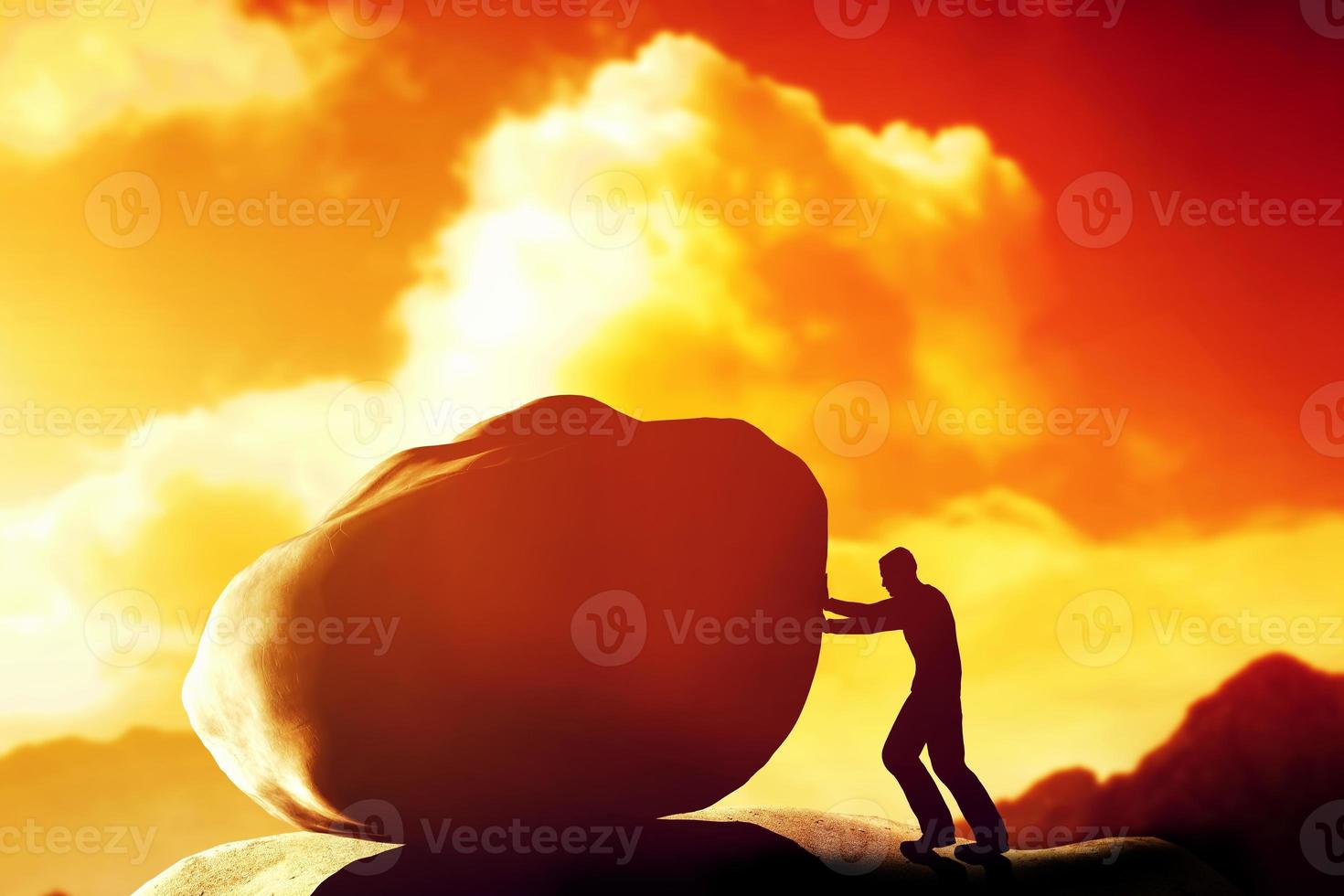 Man pushing a giant, heavy stone, rock over the mountain. photo