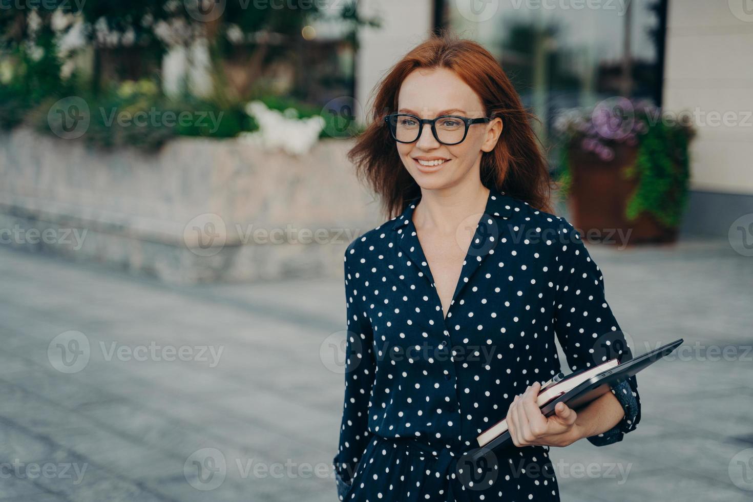 Female office worker poses outside with organizer modern gadgets photo