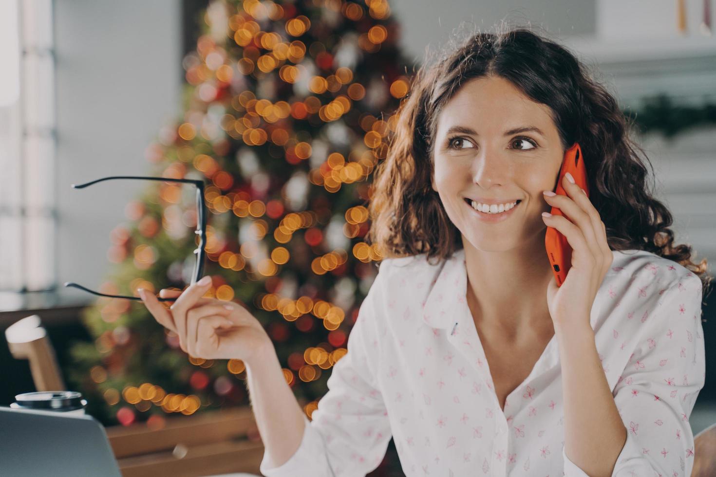 Young happy european businesswoman speaking on mobile phone with customer during winter holidays photo