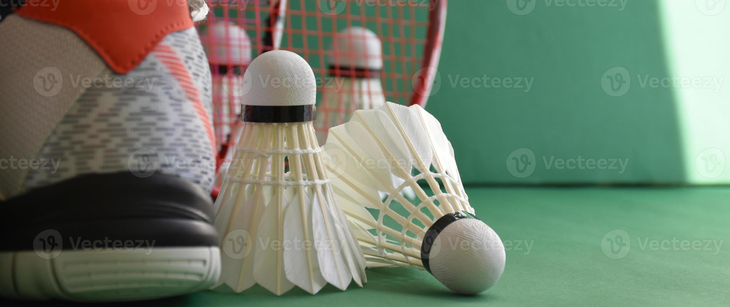 equipos deportivos de bádminton en el piso verde de los volantes de la cancha de bádminton, raquetas, zapatos, enfoque selectivo en los volantes, concepto de amante del deporte del bádminton en todo el mundo. foto