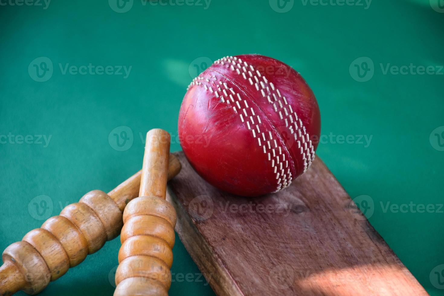primer plano de equipos deportivos de cricket antiguos en suelo verde, pelota de cuero antigua, wickets de madera y bate de madera, enfoque suave y selectivo, concepto tradicional de los amantes del deporte de cricket en todo el mundo. foto