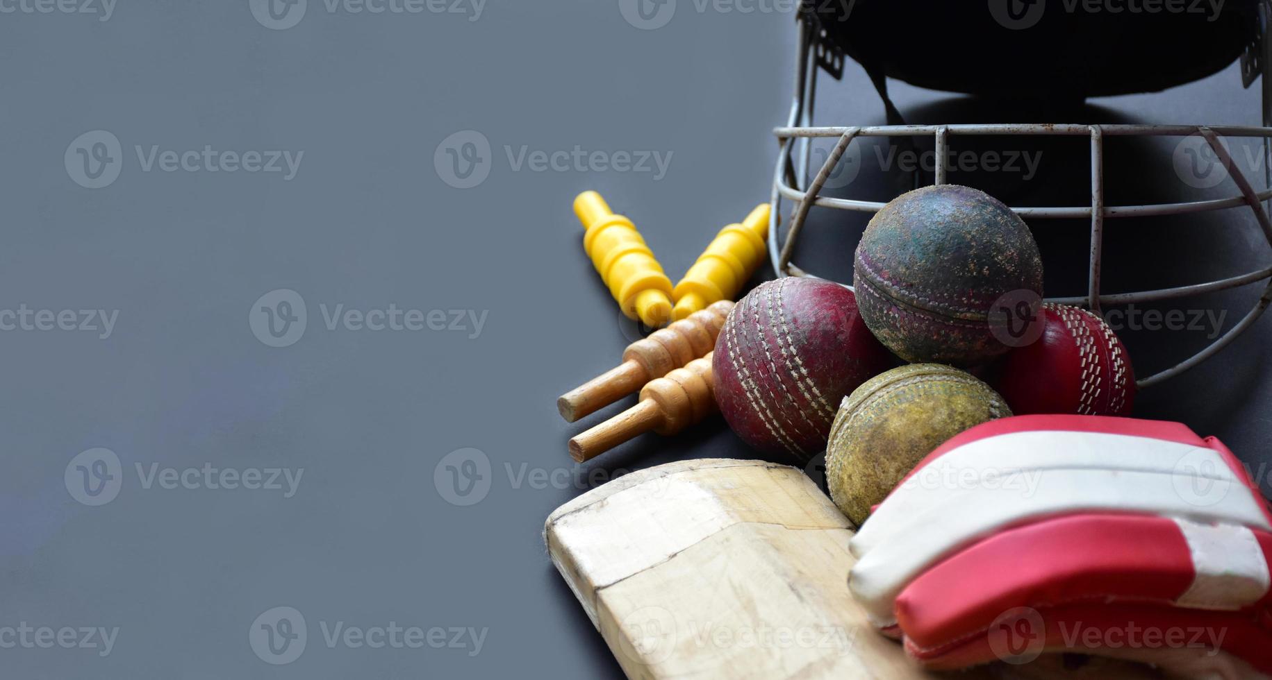 Old training cricket sport equipments on dark floor, leather ball, wickets, helmet and wooden bat, soft and selective focus, traditional cricket sport lovers around the world concept. photo