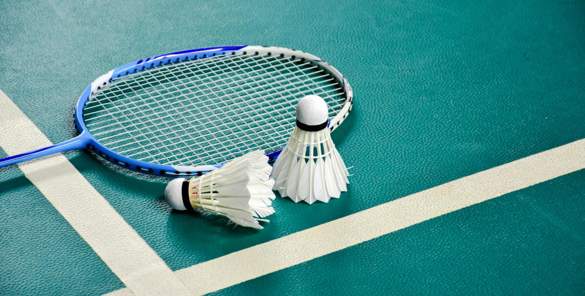 equipos deportivos de bádminton en volantes de piso verde, raquetas, zapatos, enfoque selectivo en volantes, concepto de amante del deporte de bádminton. foto