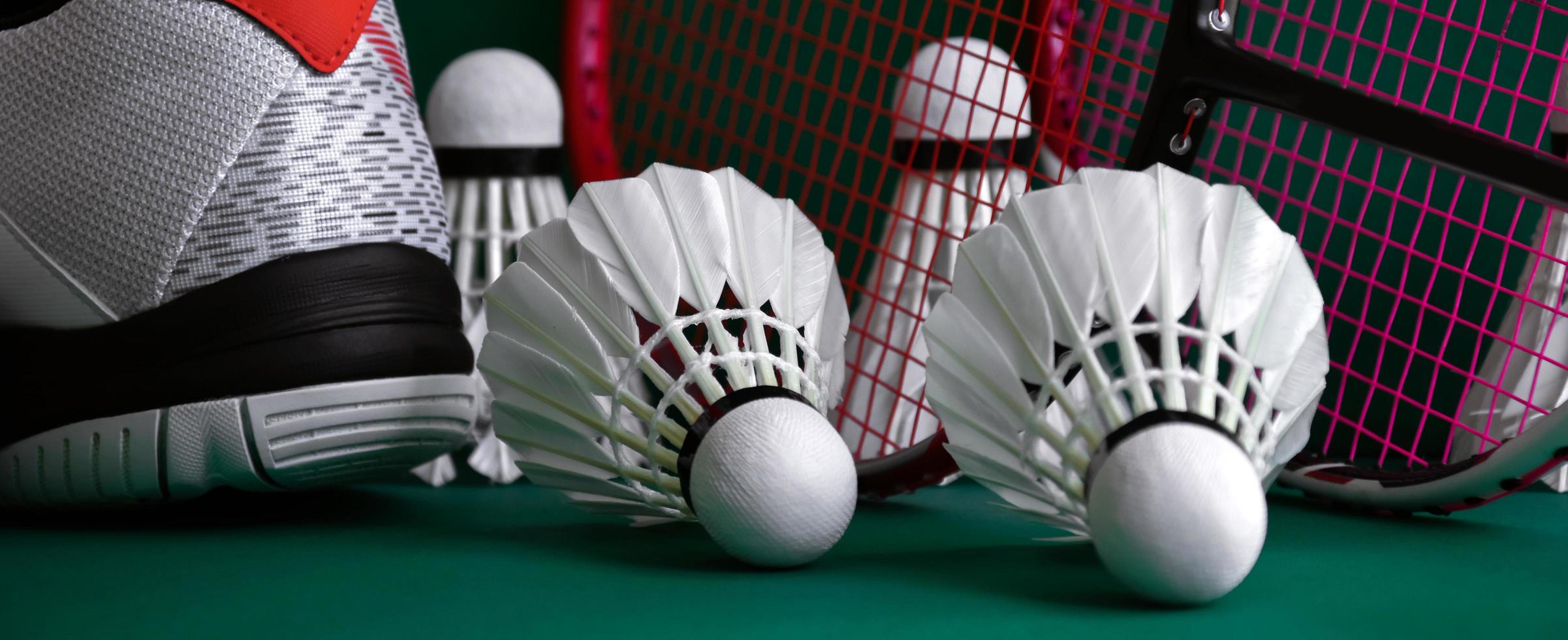 Badminton sport equipments on green floor shuttlecocks, rackets, shoes, selective focus on shuttlecocks, badminton sport playing lover concept. photo