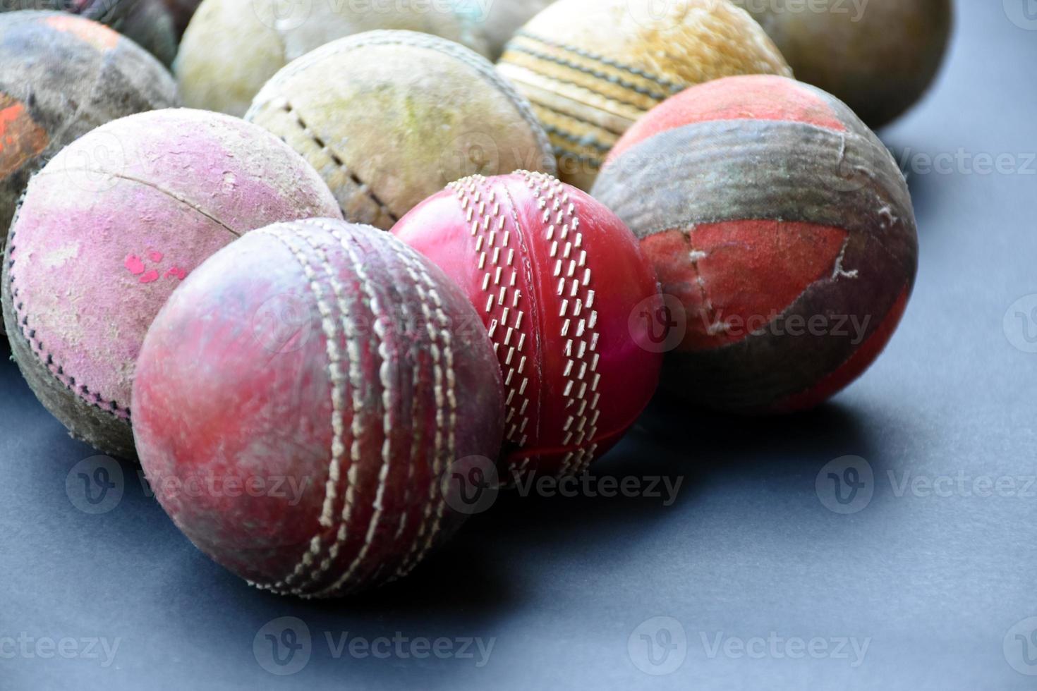 Old training cricket sport equipments on dark floor, leather ball, wickets, helmet and wooden bat, soft and selective focus, traditional cricket sport lovers around the world concept. photo