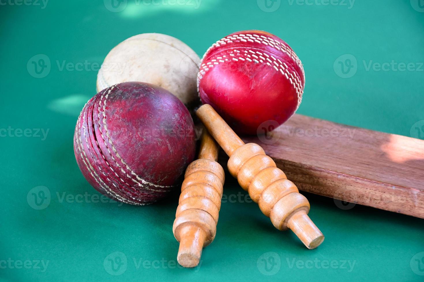 primer plano de equipos deportivos de cricket antiguos en suelo verde, pelota de cuero antigua, wickets de madera y bate de madera, enfoque suave y selectivo, concepto tradicional de los amantes del deporte de cricket en todo el mundo. foto