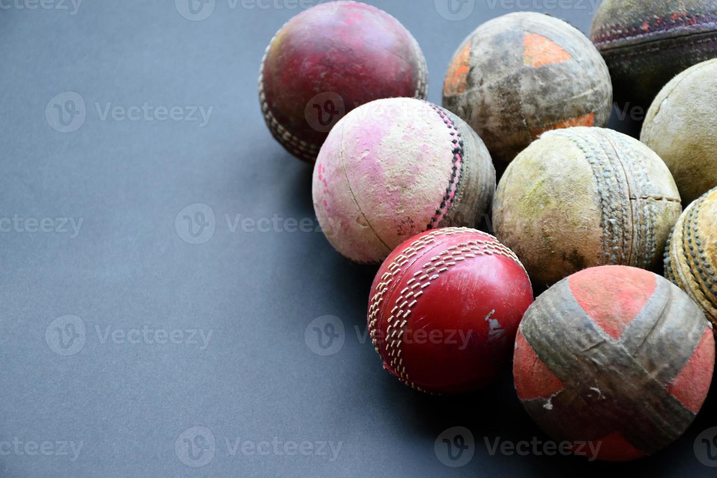 antiguos equipos deportivos de cricket de entrenamiento en suelo oscuro, pelota de cuero, wickets, casco y bate de madera, enfoque suave y selectivo, concepto tradicional de amantes del deporte de cricket en todo el mundo. foto