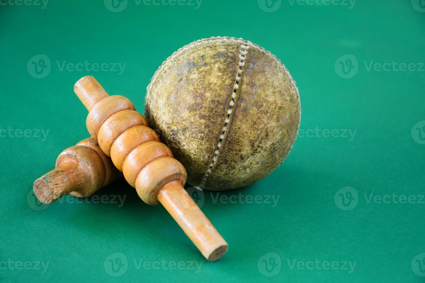 Closeup old cricket sport equipments on green floor, old leather ball and wooden wickets, soft and selective focus, traditional cricket sport lovers around the world concept. photo