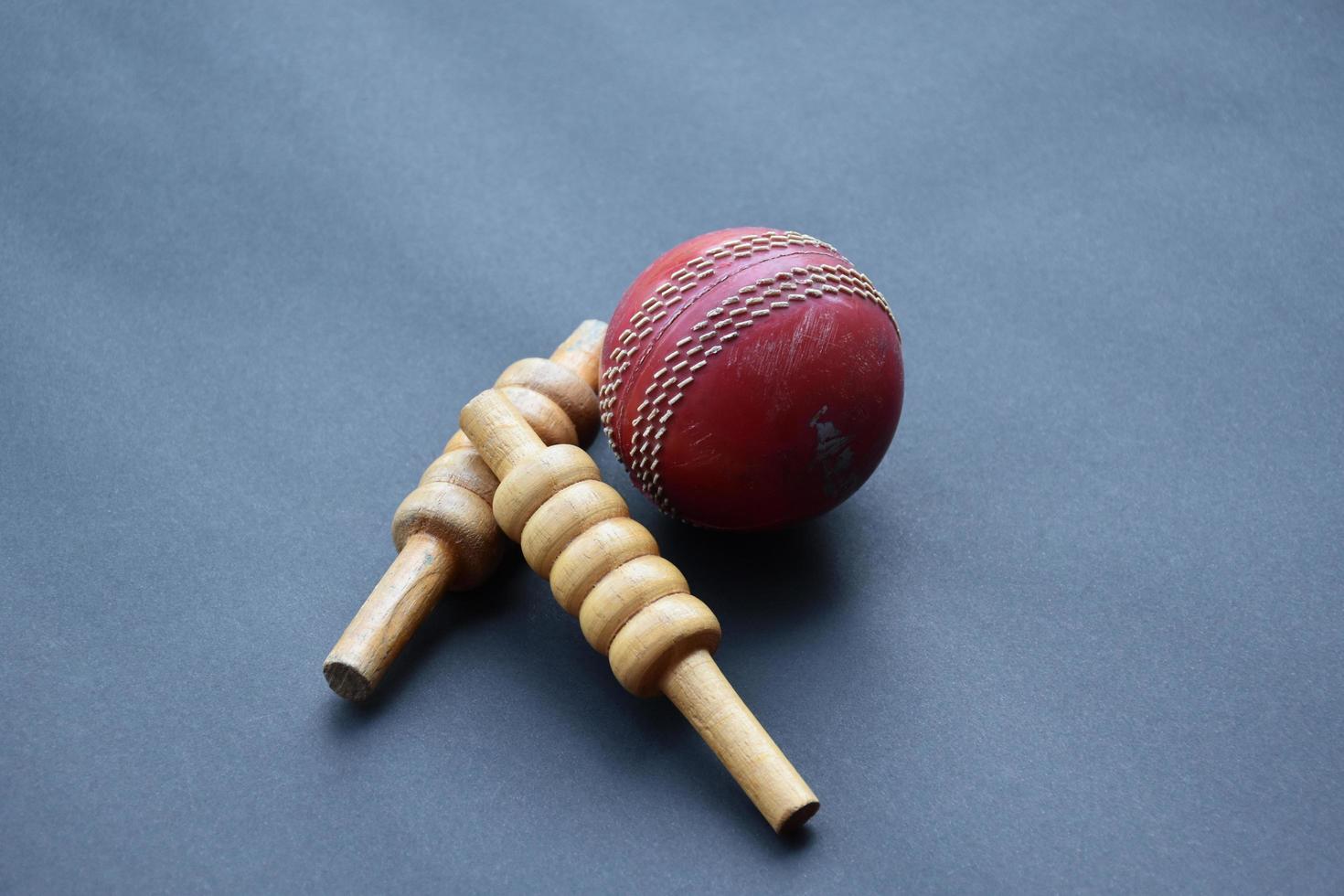 Old training cricket sport equipments on dark floor, leather ball, wickets, helmet and wooden bat, soft and selective focus, traditional cricket sport lovers around the world concept. photo