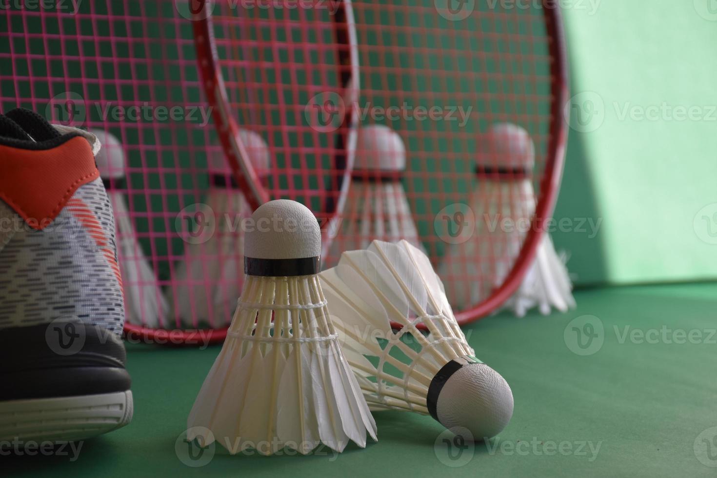 equipos deportivos de bádminton en el piso verde de los volantes de la cancha de bádminton, raquetas, zapatos, enfoque selectivo en los volantes, concepto de amante del deporte del bádminton en todo el mundo. foto