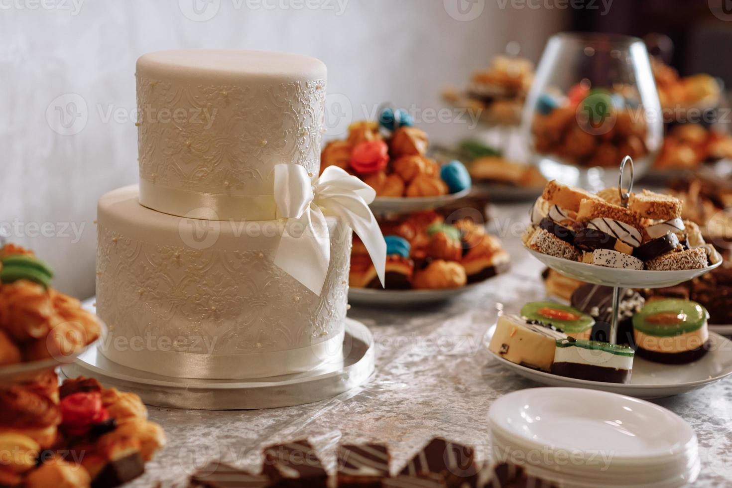 pastel de bodas blanco. detalle del pastel de bodas: una cinta con perlas. barra de caramelo foto