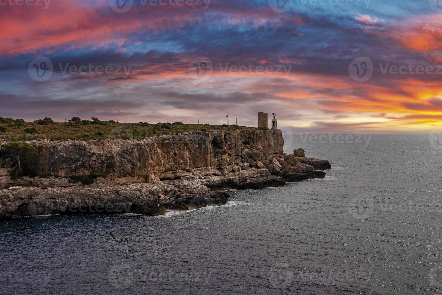 Idyllic view of seascape by cliff against dramatic sky during sunset photo