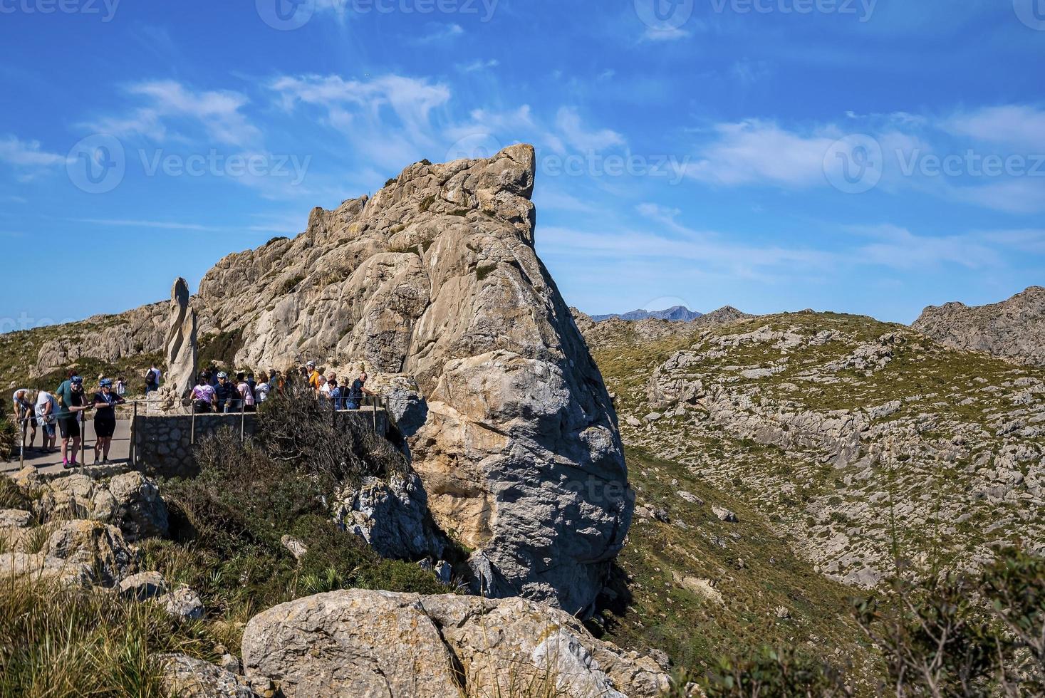 Tourists exploring rocky cliffs against blue sky during summer vacation photo
