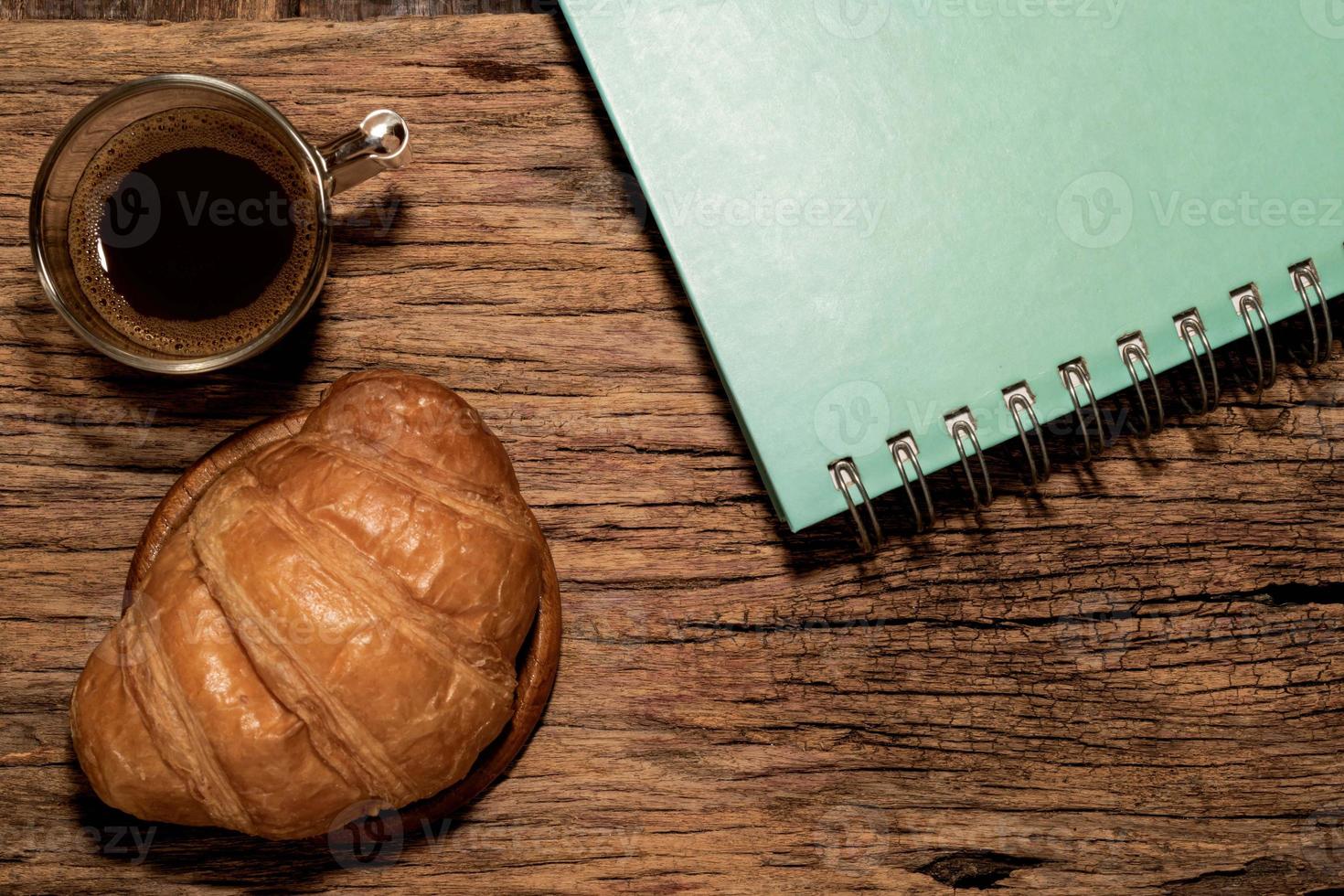 desayuno comida croissant en plato y café en mesa de madera. foto