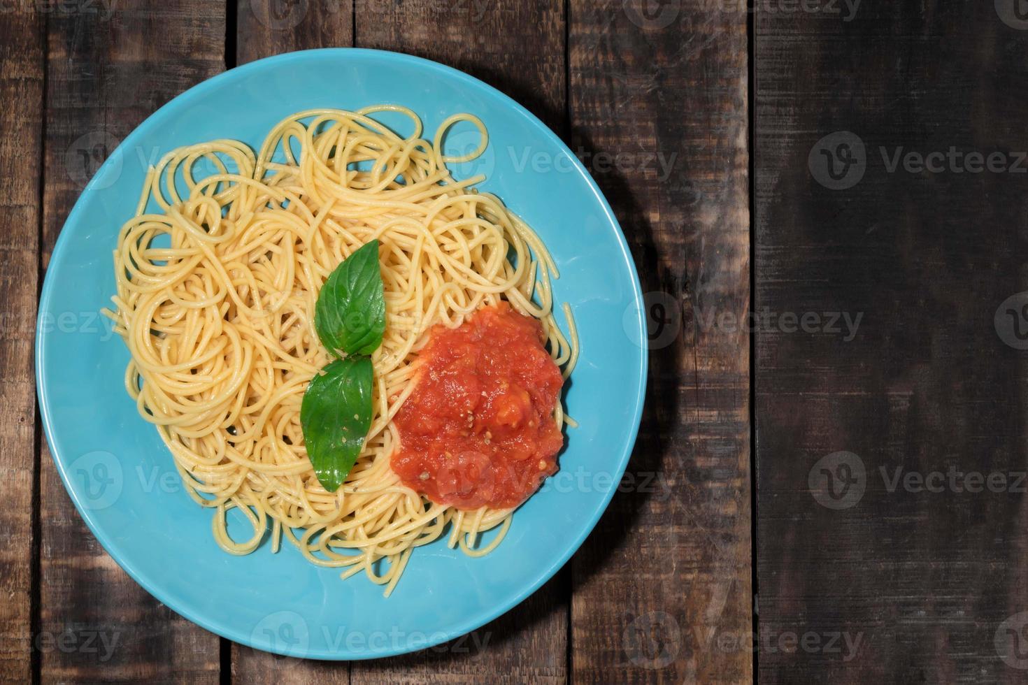 pasta con salsa de tomate en plato azul sobre fondo de madera foto