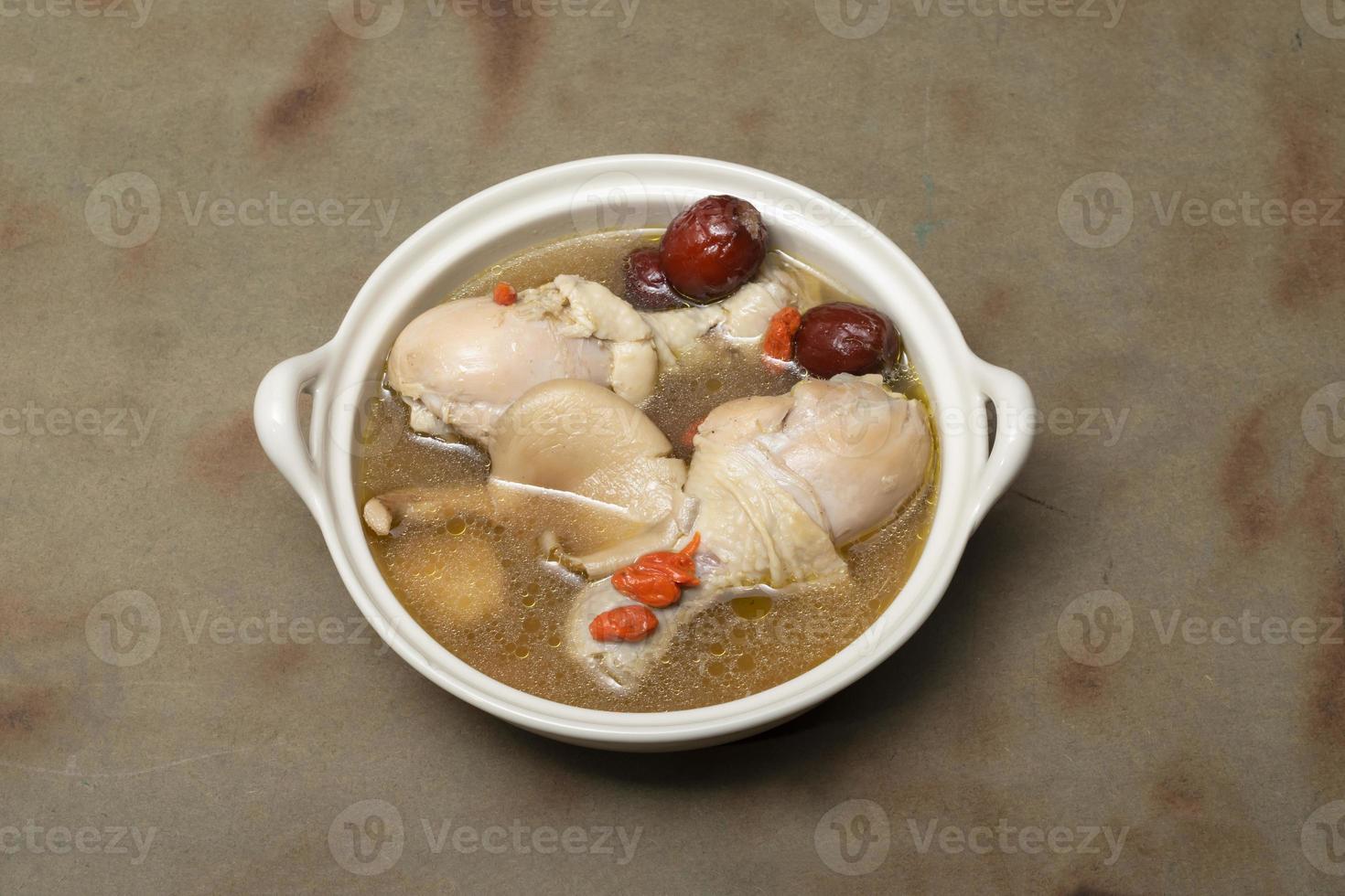 Chinese chicken soup has herb on wood table. photo