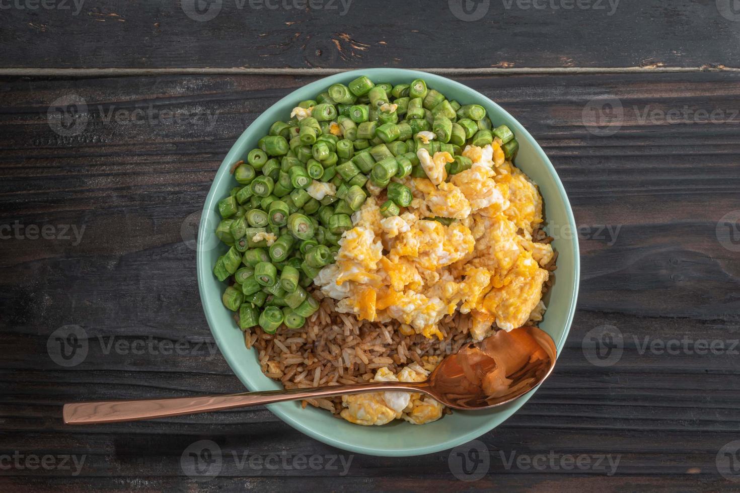 arroz frito con huevo y frijoles en un tazón verde sobre una mesa de madera. foto