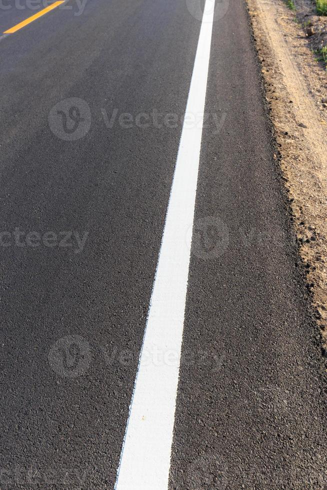 línea blanca y amarilla en la nueva carretera asfaltada foto